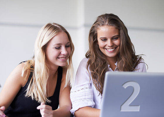 Două tinere care se uită la ecranul laptopului