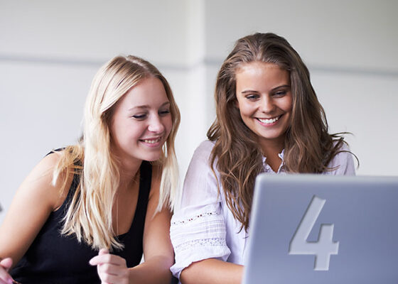 Două tinere care se uită la ecranul laptopului